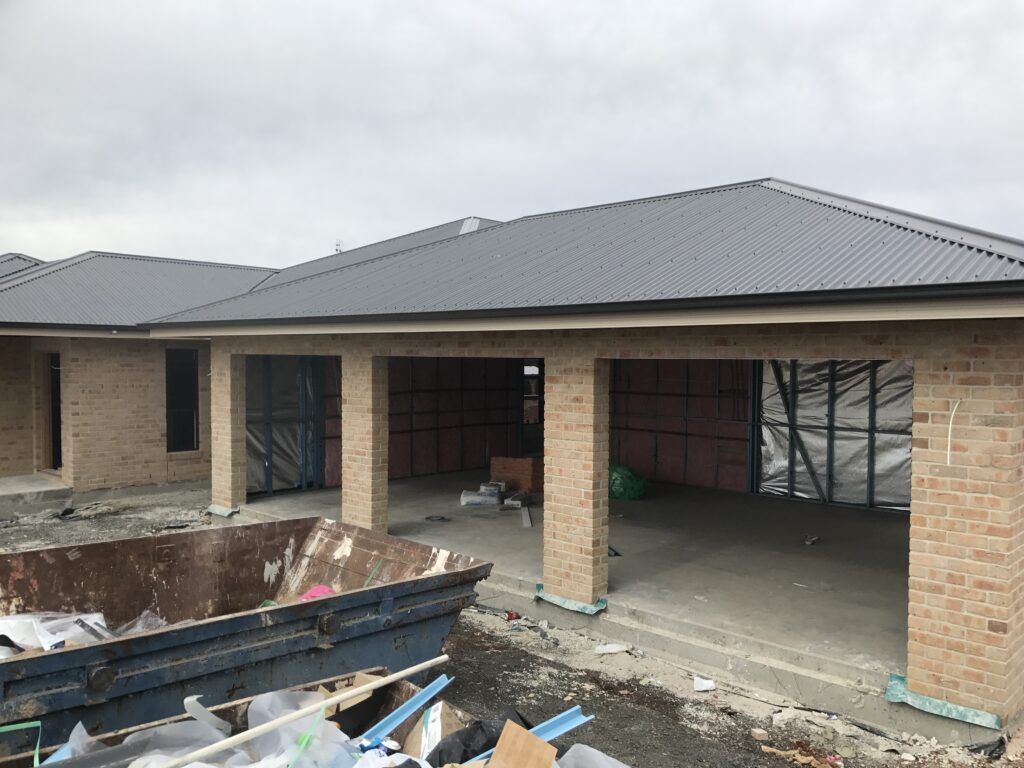 A partially constructed brick house with a metal roof