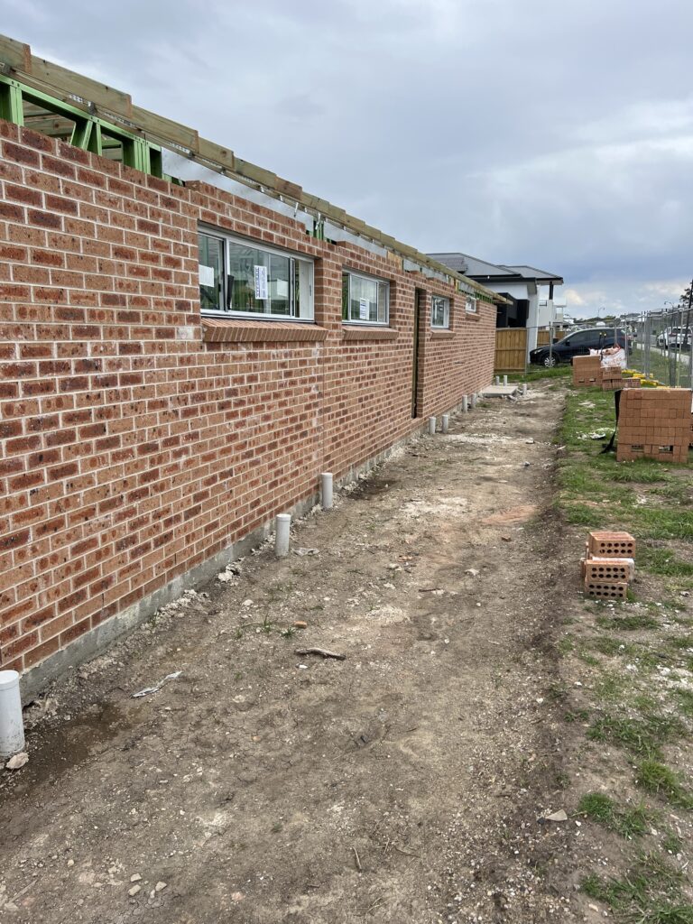 Red brick wall with several small, rectangular windows under construction